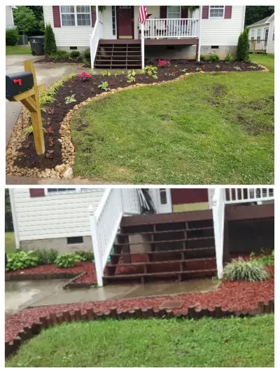 A residential front yard features newly installed dark mulch beds bordered by natural stones, leading up to a wooden porch with white railings.